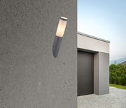 Moderne Außenleuchte BOSTON an einer Betonwand, seitliche Perspektive, mit einem Haus im Hintergrund.