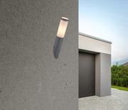 Moderne Außenleuchte BOSTON an einer Betonwand, seitliche Perspektive, mit einem Haus im Hintergrund.
