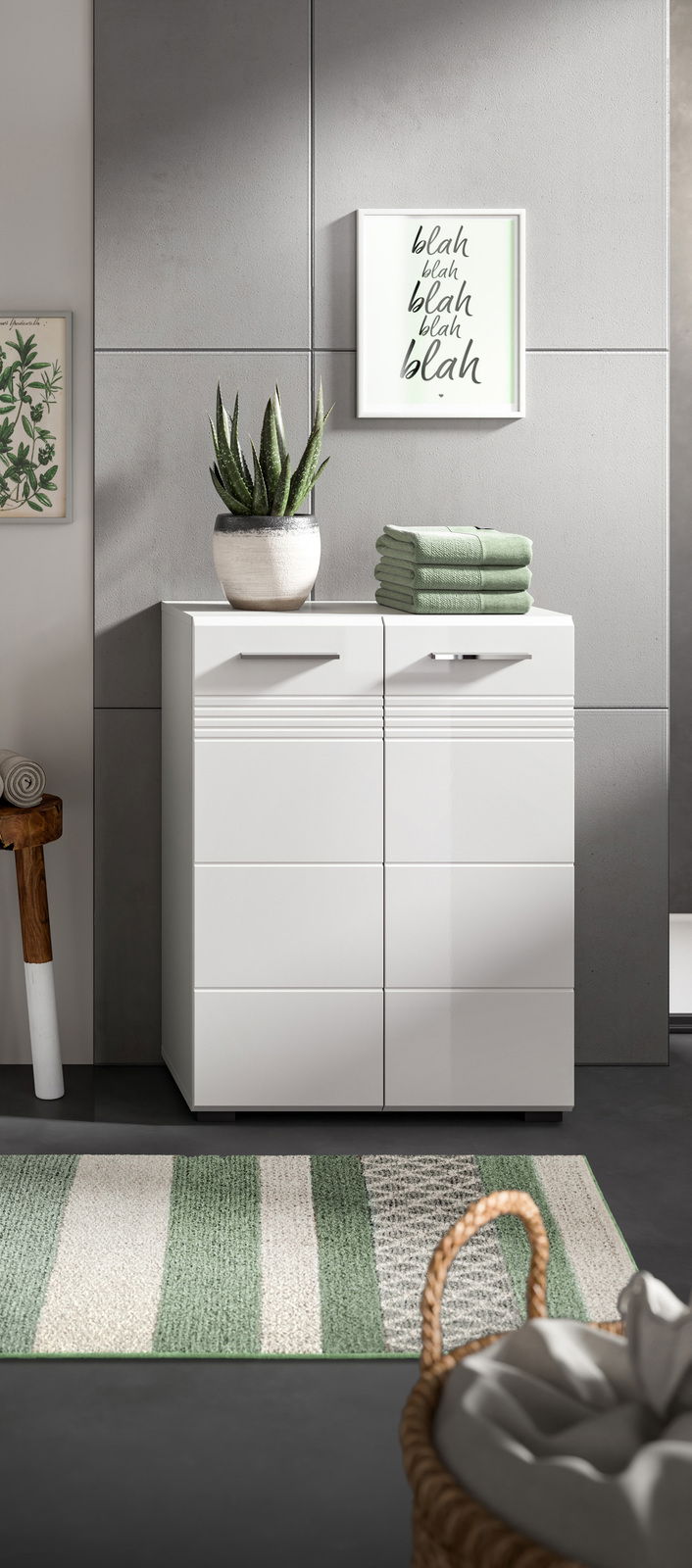 Moderner weißer Midischrank mit zwei Türen, dekoriert mit einem Pflanzentopf und gefalteten Handtüchern, aus frontaler Perspektive.