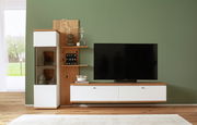 Frontale Ansicht der Wandkombination Novel MATADI mit weißem und holzfarbenem Design, bestehend aus einem TV-Schrank, einem Vitrinenschrank und Regalböden, vor einer grünen Wand.