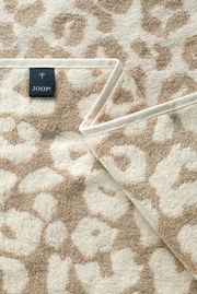 Nahaufnahme eines beigen Saunatuchs mit floralem Muster und einem Joop-Label.