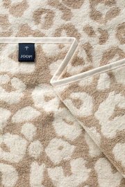 Nahaufnahme eines beigen Saunatuchs mit floralem Muster und einem Joop-Label.
