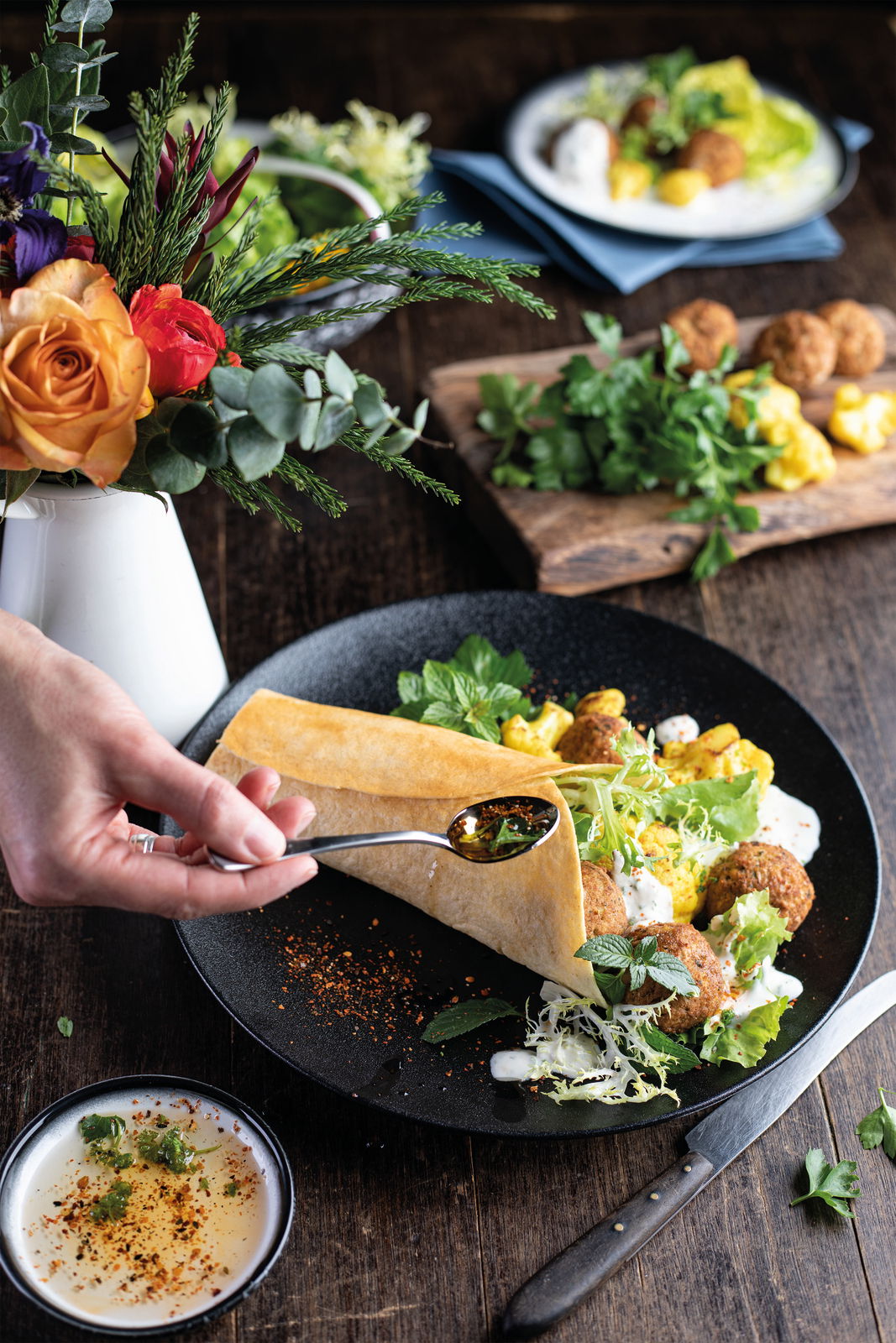 Nahaufnahme eines stilvoll angerichteten Tellers aus dem Dinner-Set Caviar black mit frischen Zutaten und einer Hand, die einen Löffel hält.