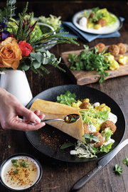 Nahaufnahme eines stilvoll angerichteten Tellers aus dem Dinner-Set Caviar black mit frischen Zutaten und einer Hand, die einen Löffel hält.