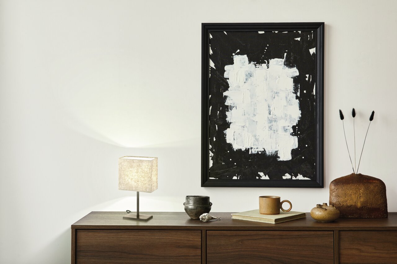 Tischleuchte Kate mit rechteckigem Stoffschirm auf einem Holzschrank, seitliche Perspektive