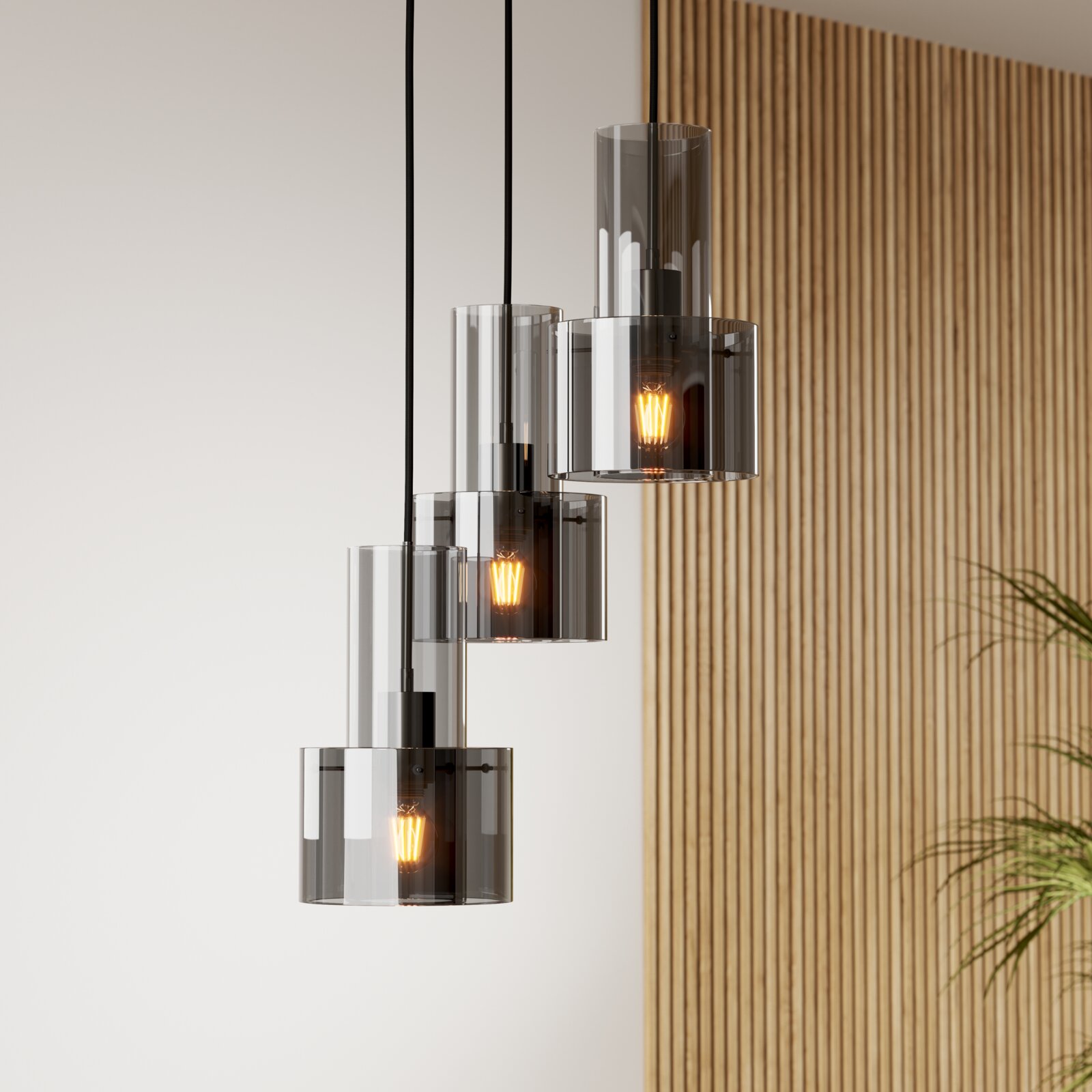 Moderne Pendelleuchte mit drei rauchgrauen Glaszylindern und warm leuchtenden Filament-Leuchtmitteln, an schwarzen Kabeln hängend, in leichter Seitenansicht vor heller Wand mit Holzlamellen