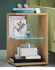 Moderner Beistelltisch aus Holz mit offenem Fach und Glasablage, seitliche Frontansicht neben grünem Sofa, dekoriert mit Büchern, Brille und Glasdose.