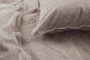 Nahaufnahme einer Bettwäsche in Beige mit Kissenbezug, aus der Vogelperspektive fotografiert.