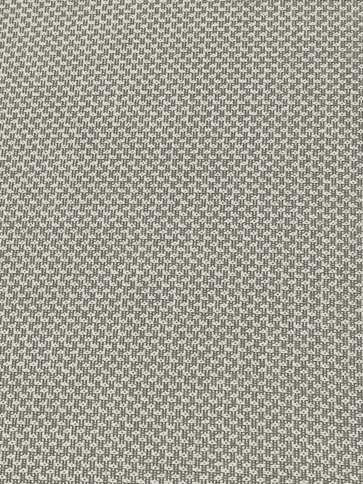 Nahaufnahme eines Stoffmusters in Grau und Weiß mit kleinem geometrischem Muster, von oben betrachtet.