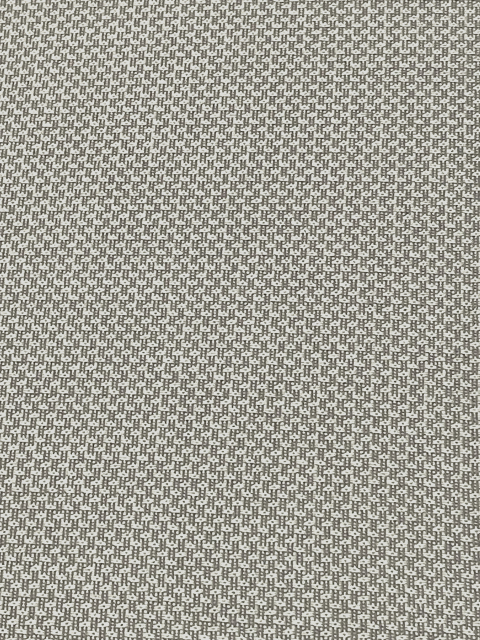 Nahaufnahme eines Stoffmusters in Grau und Weiß mit kleinem geometrischem Muster, von oben betrachtet.