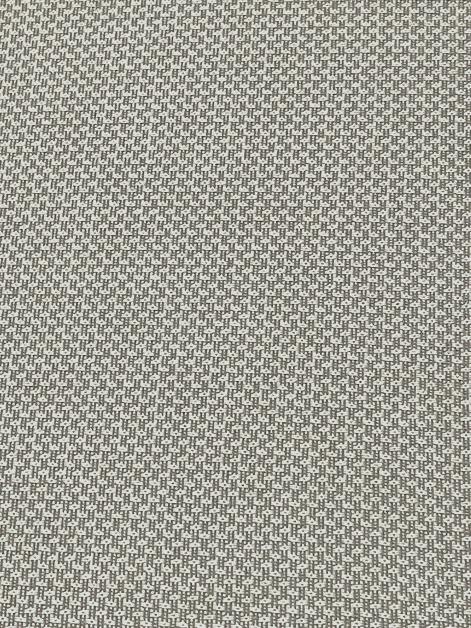 Nahaufnahme eines Stoffmusters in Grau und Weiß mit kleinem geometrischem Muster, von oben betrachtet.