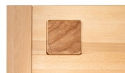 Detailfoto van een salontafel van licht hout met een vierkant inzetstuk van donkerder hout.
