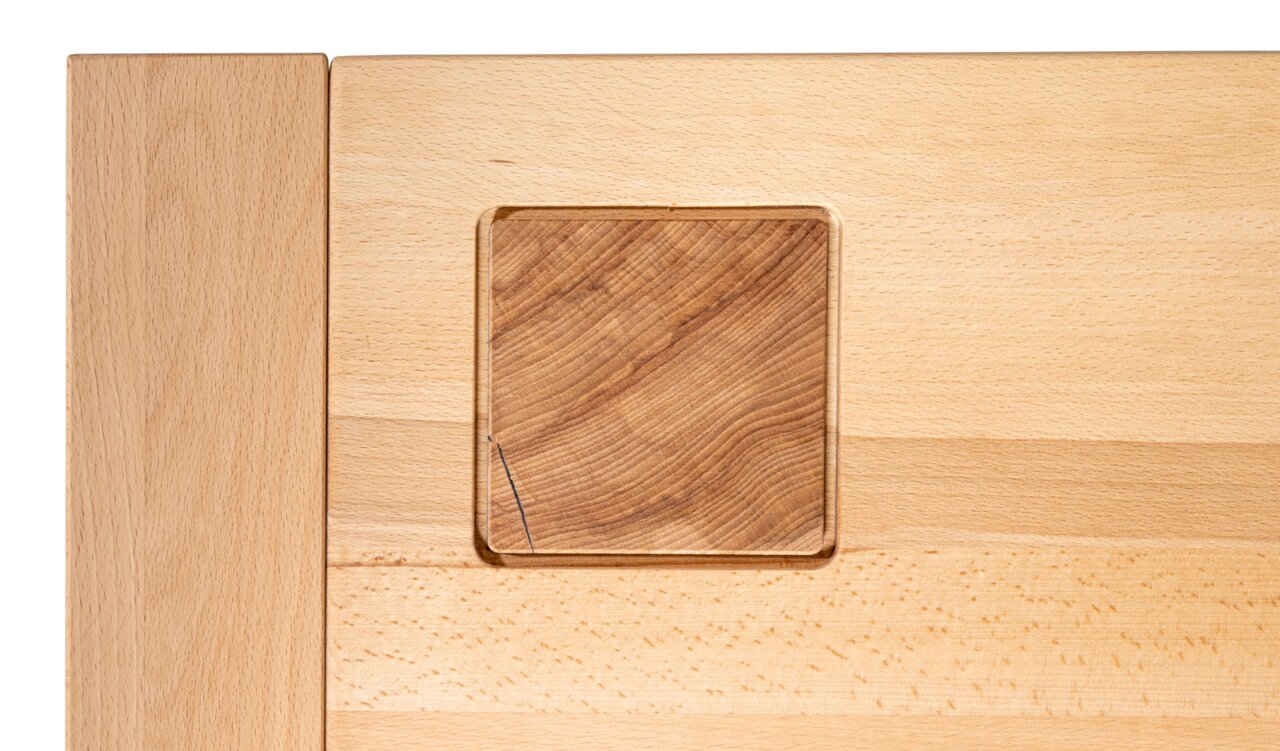 Detailfoto van een salontafel van licht hout met een vierkant inzetstuk van donkerder hout.