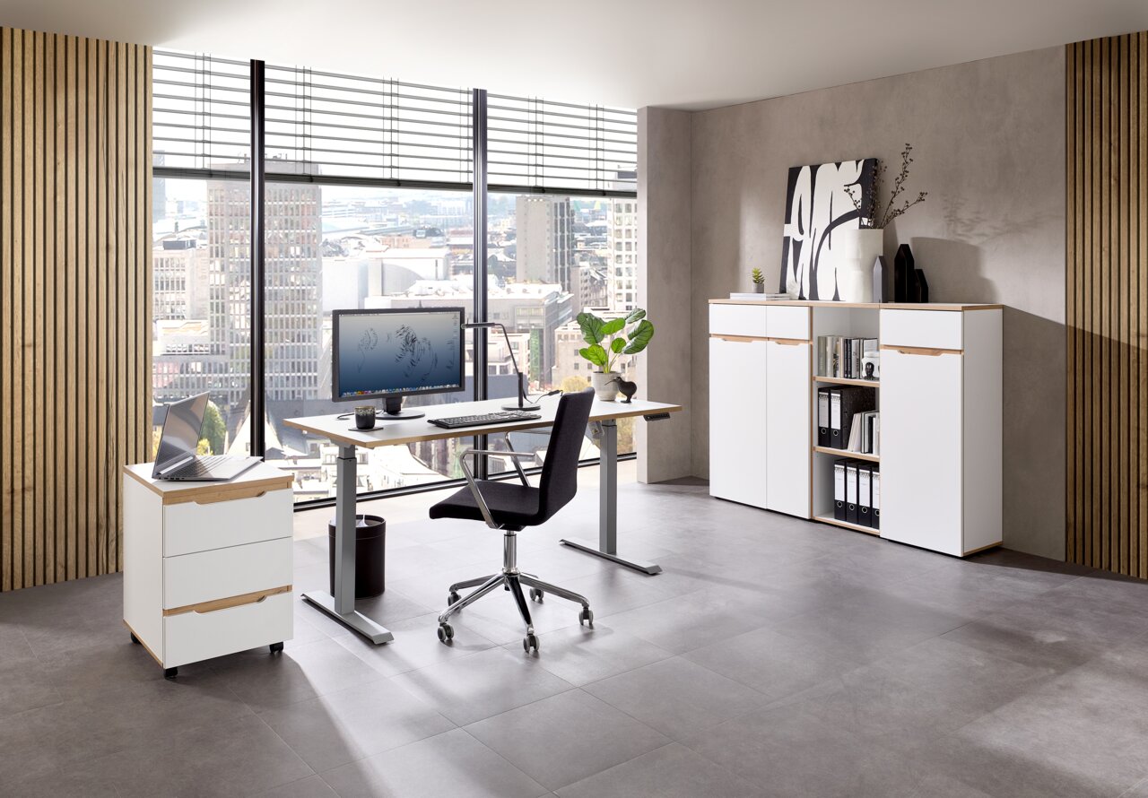 Voleo E-Schreibtisch DETROIT Modernes Büro mit einem höhenverstellbaren Schreibtisch, einem Rollcontainer und einem Aktenschrank, mit Blick auf die Stadt durch große Fenster.