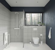 Moderne Badezimmeransicht mit WC-Bürste aus Stahl in Weiß neben der Toilette, von vorne betrachtet.