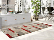 Moderner Teppich in Beige- und Rottönen, rechteckig, auf hellem Holzboden in einem stilvoll eingerichteten Raum mit Pflanzen und Dekorationen, seitliche Perspektive.