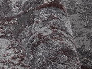 Nahaufnahme eines Designer-Teppichs mit grauen und roten Mustern, aus seitlicher Perspektive aufgenommen.