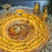 LED-Kranz mit warmweißen Lichtern, umgeben von Kerzen und Snacks auf einem flauschigen Teppich, aus der Vogelperspektive.