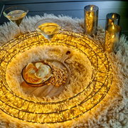 LED-Kranz mit warmweißen Lichtern, umgeben von Kerzen und Snacks auf einem flauschigen Teppich, aus der Vogelperspektive.