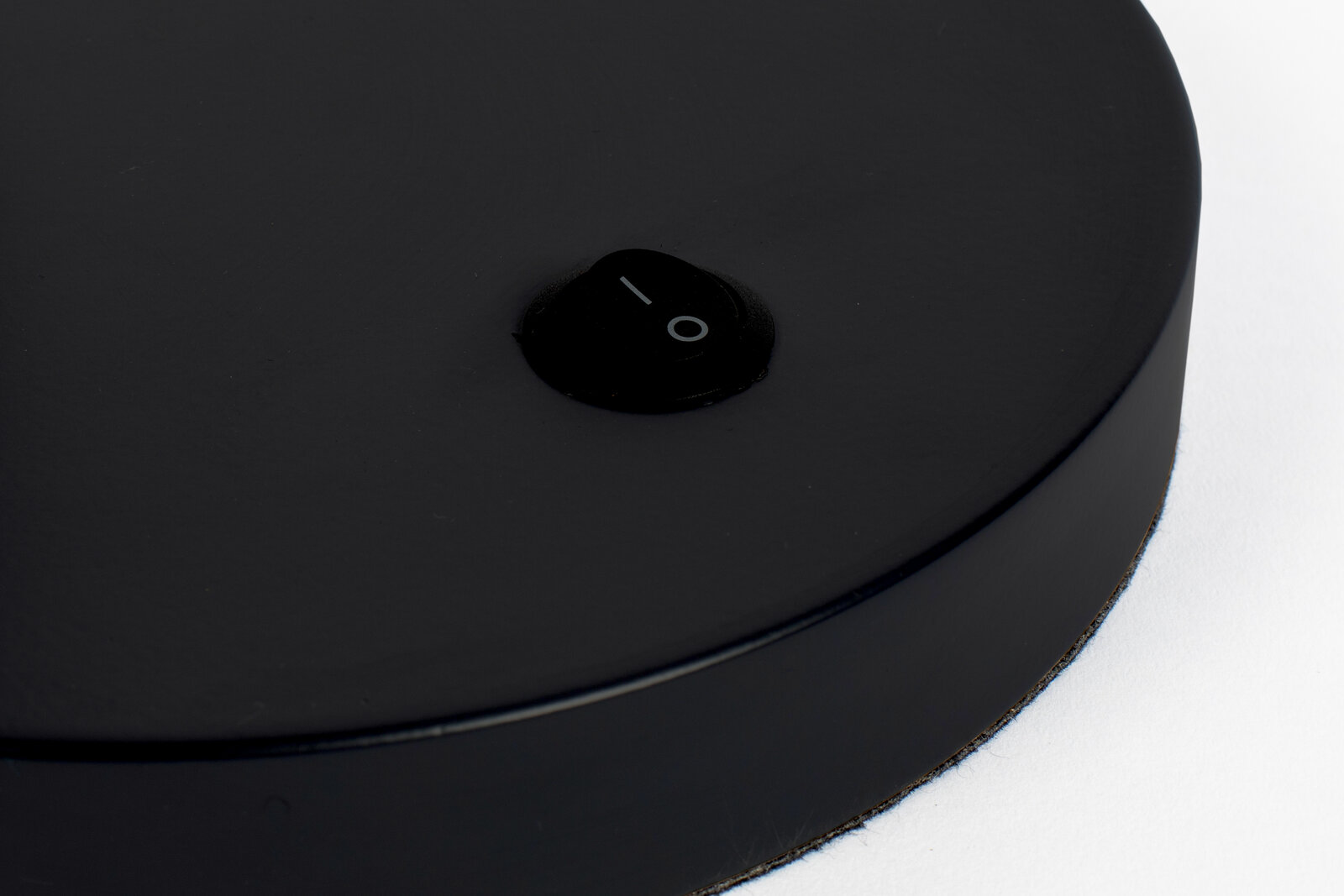 Nahaufnahme eines schwarzen Schalters auf der Basis einer Schreibtischleuchte, von oben betrachtet.