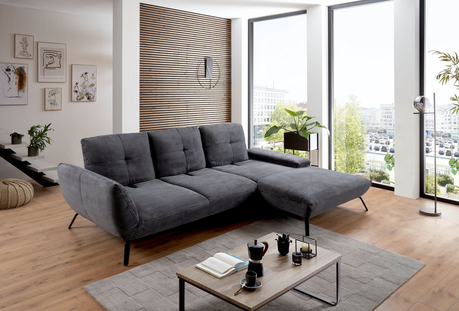 Graues Ecksofa in modernem Wohnzimmer mit Holzboden und großen Fenstern, seitliche Perspektive