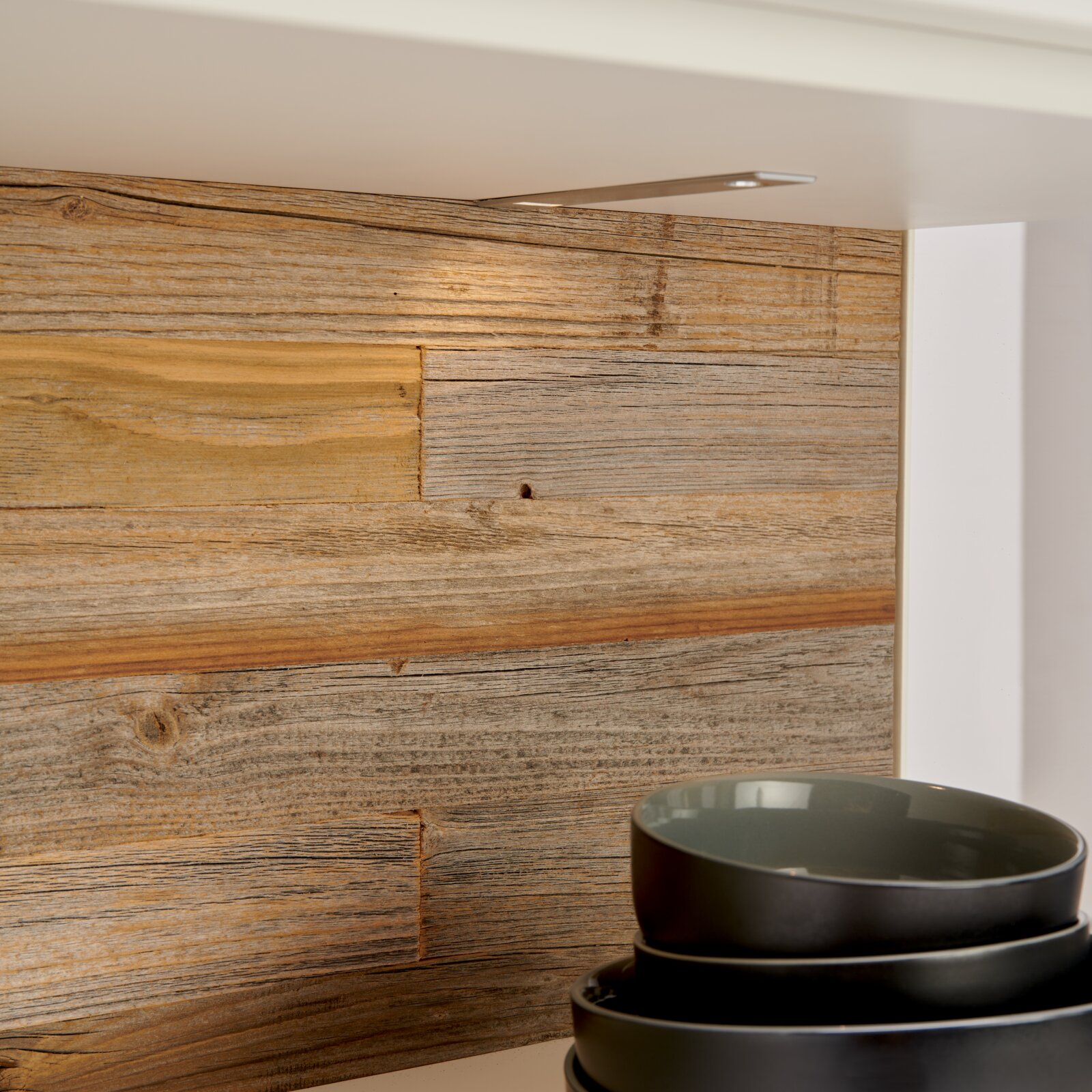Detailfoto van een dressoir met houten achterwand en gestapelde schalen op de voorgrond.