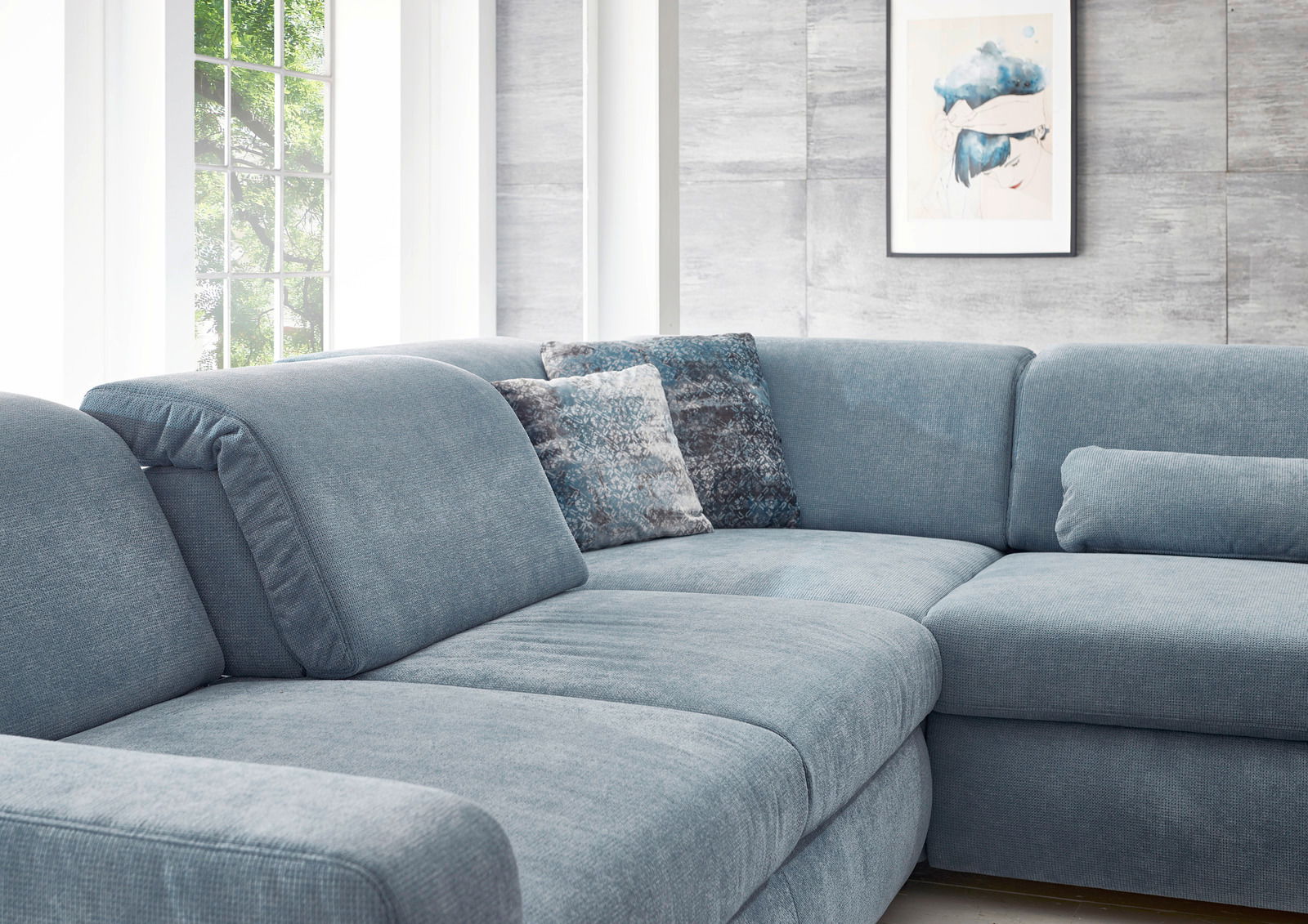 Blaue Polsterrundecke in einem modernen Wohnzimmer, seitliche Perspektive mit dekorativen Kissen und einem großen Fenster im Hintergrund.