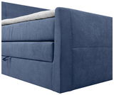 Nahaufnahme eines blauen Boxspringbetts von der Seite, mit sichtbarer Matratze und Stoffbezug.