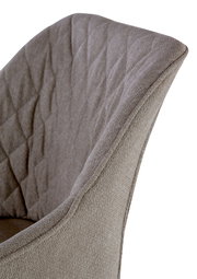 Nahaufnahme eines Armlehnstuhls mit gepolstertem, gestepptem Stoff in Beige, seitliche Perspektive.