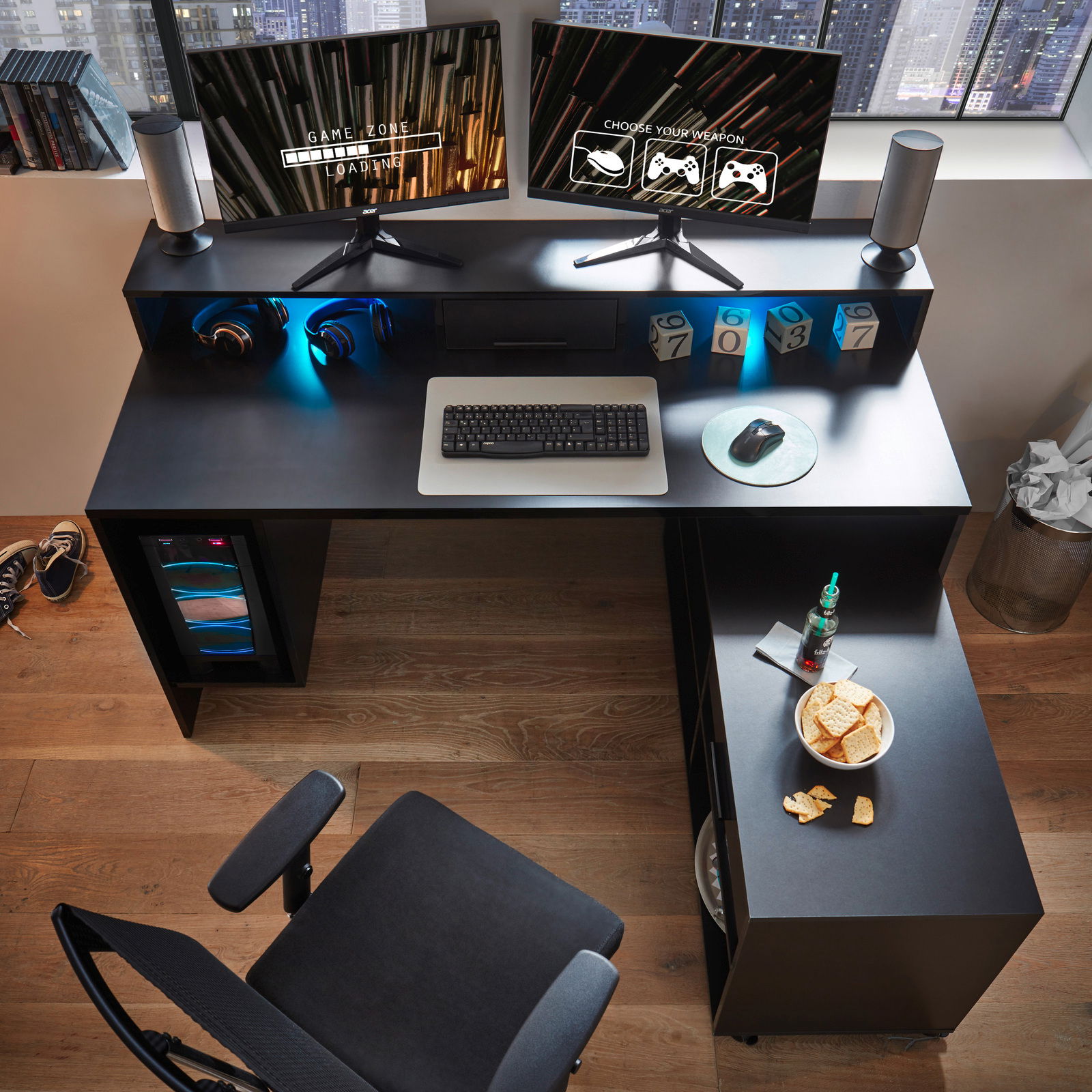 Gaming-Schreibtisch mit zwei Monitoren, Tastatur und Maus aus der Vogelperspektive, umgeben von Kopfhörern, Lautsprechern und Snacks.