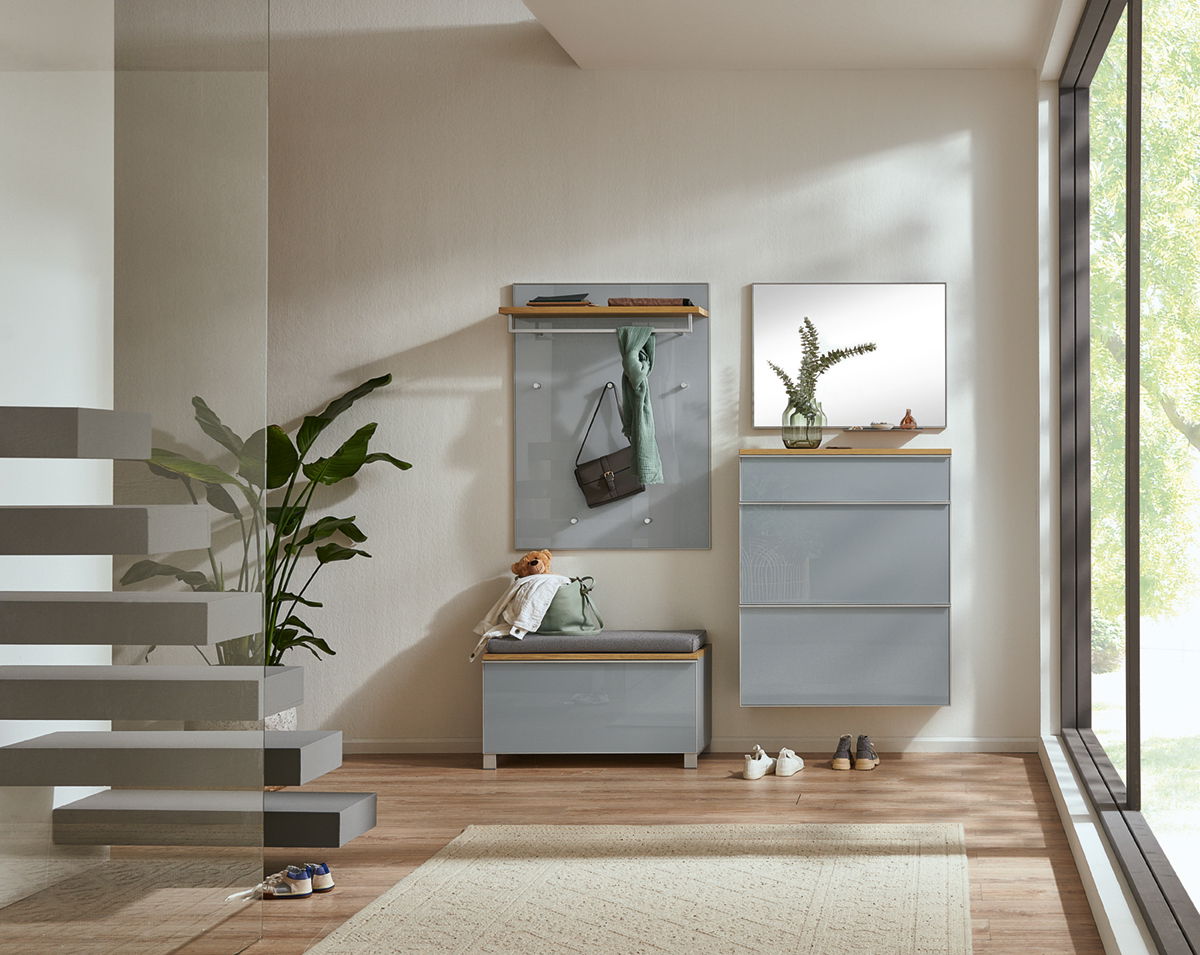 Moderne Garderobeneinrichtung mit Hängeschuhschrank, Garderobenbank und Spiegel in einem hellen Raum mit Blick auf eine große Fensterfront.