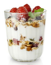 Facettenglas mit Joghurt, Müsli, Himbeeren und Minzblatt, seitliche Perspektive