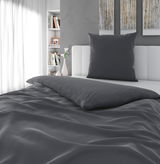 Graue Bettwäsche auf einem Bett mit Kopfkissen, seitliche Perspektive