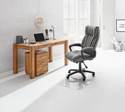 Moderner Schreibtisch aus Holz mit Schubladen, seitliche Perspektive, ausgestattet mit Laptop, Lampe und Büromaterialien, daneben ein grauer Bürostuhl auf einer transparenten Bodenmatte.