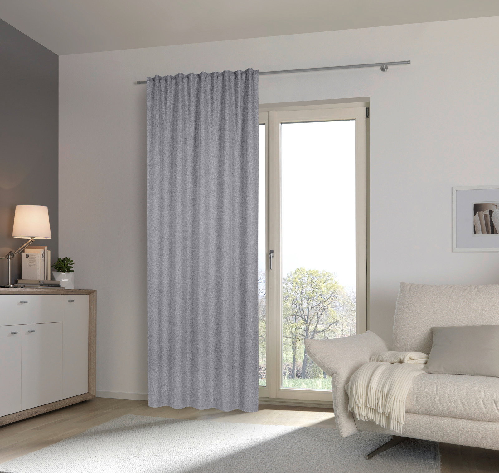 Grauer Fertigvorhang in einem modernen Wohnzimmer, aufgehängt an einer Gardinenstange vor einer Glastür, seitliche Perspektive