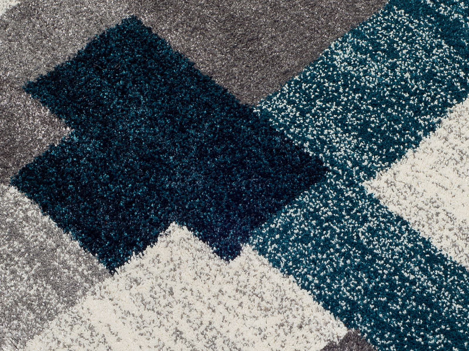 Nahaufnahme eines Frisé-Teppichs mit geometrischem Muster in Grau, Blau und Weiß.