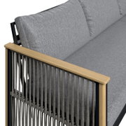 Detailansicht eines Lounge-Sofas mit grauen Kissen und Holzarmlehne, seitliche Perspektive