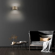 Moderne Wandleuchte PURE Clipse in einem stilvollen Wohnzimmer, frontal an der Wand montiert, mit sanftem Lichtschein.