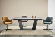 Moderne eettafel met een zwart onderstel en een grijs tafelblad, omringd door drie gekleurde stoelen in een lichte ruimte, gezien van voren.