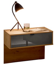 Moderner Nachtschrank aus Holz mit einer Schublade in dunklem Glas, darauf eine stilvolle Lampe und ein Glas Wasser, seitliche Perspektive.