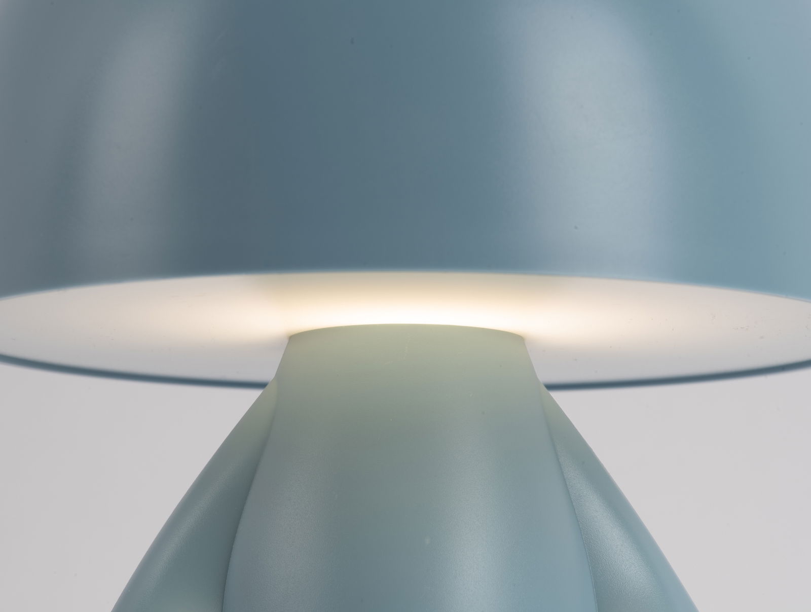 Nahaufnahme einer blauen LED-Tischlampe mit leuchtendem Schirm, seitliche Perspektive.