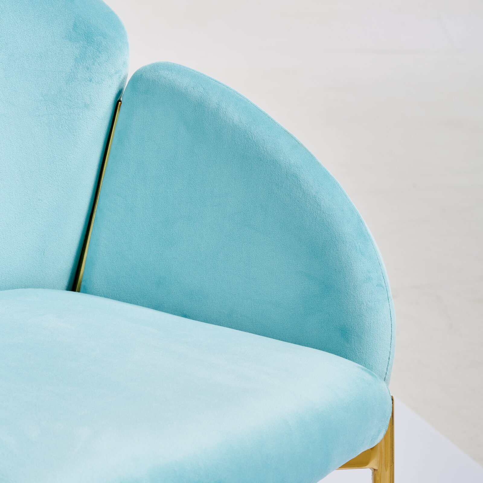 Turquoise fauteuil met gouden accenten, close-up vanaf de zijkant