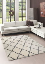 Moderner Wohnzimmerteppich mit marokkanischem Muster in Creme und Schwarz, perspektivisch von oben fotografiert, in einem stilvollen Wohnzimmer mit weißem Ecksofa.