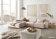 Moderne Wohnzimmeransicht mit einer großen, beigen Eckcouch in einem hellen Raum mit großen Fenstern, einem flauschigen Teppich und stilvollen Wandbildern.