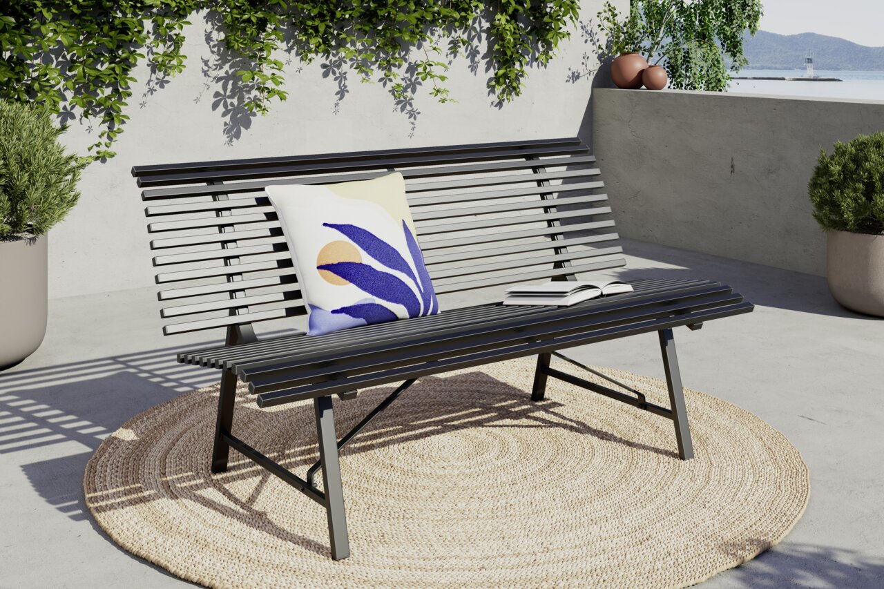 Moderne Gartenbank aus Metall mit Kissen und Buch, seitliche Perspektive, auf einer Terrasse mit Pflanzen im Hintergrund.