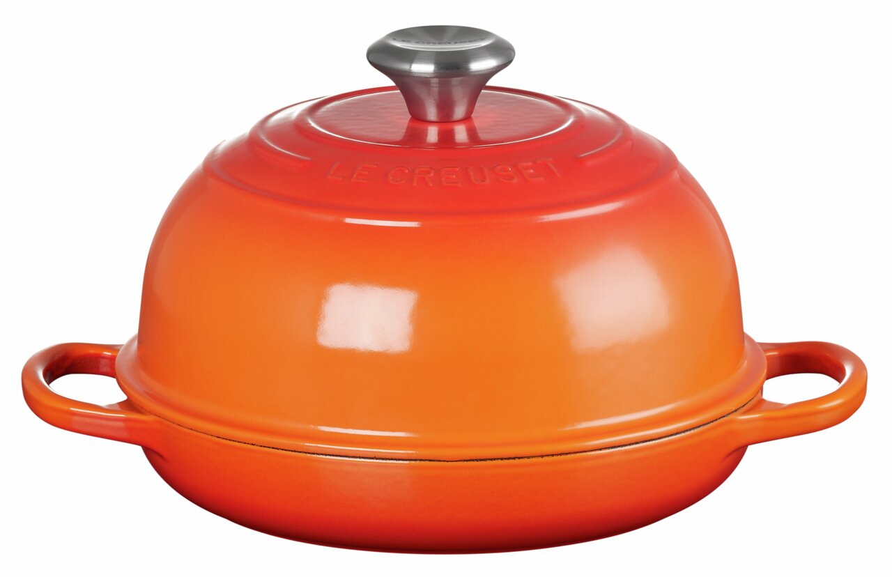 Rode broodbraadpan van Le Creuset, zijaanzicht, met twee handgrepen en een rond deksel met metalen knop.