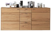 Frontale Ansicht eines modernen Sideboards aus hellem Holz mit mehreren Schubladen und Türen, dekoriert mit Geschirr und einer Kaffeemaschine.