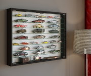 Wandmontierte schwarze Glasvitrine mit mehreren Glasböden und Sammlung von Modellautos, fotografiert in schräger Frontansicht von links.