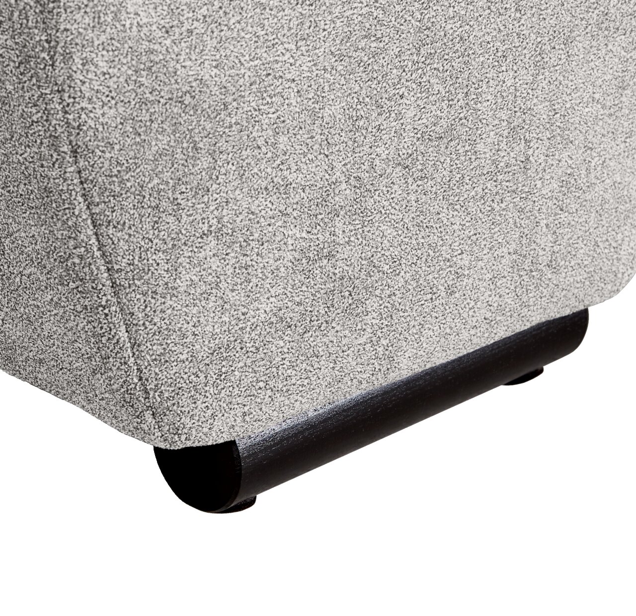 Nahaufnahme der unteren Ecke eines Big-Sofas mit grauem Stoffbezug und schwarzen Füßen.