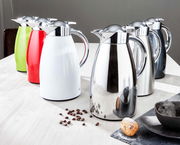 Mehrere Isolierkannen Signo aus Edelstahl in verschiedenen Farben auf einem Tisch, seitliche Perspektive.